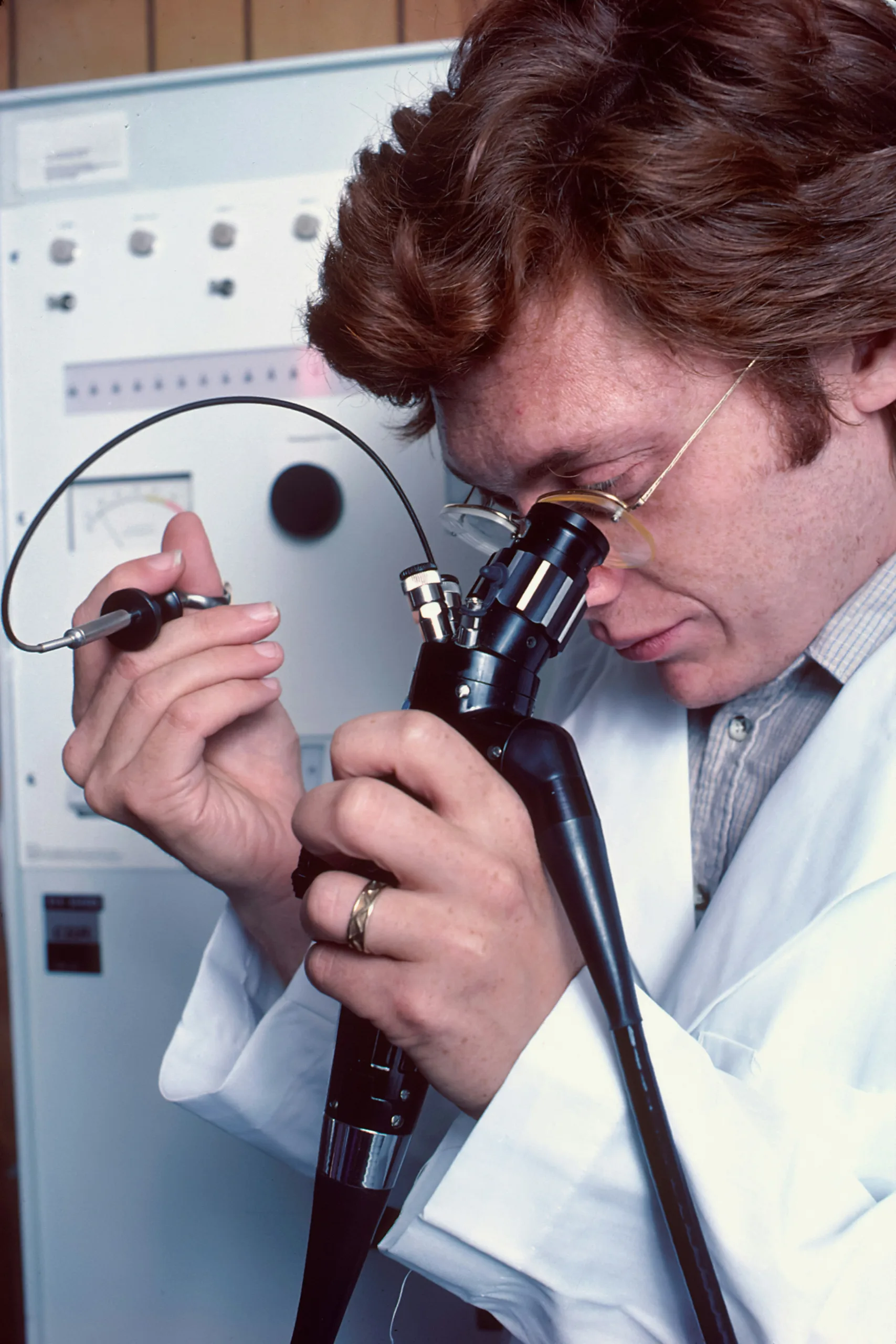 A man in a lab coat looking through a flexible bronchoscope in bronchoscopy