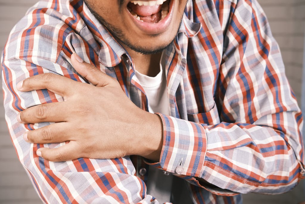 Close-up Photo of an aching Man holding his Shoulder due to arthritis